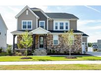 Beautiful two-story home featuring stone accents, a welcoming front porch and lush green lawn on a sunny day at 213 North Crest Dr, Chapel Hill, NC 27517