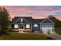 Charming home featuring a covered porch and an attached two-car garage, with a beautiful sunset at 25 Leisure Ln # 2, Louisburg, NC 27549
