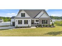 Charming two-story home with well-manicured lawn, stone accents, black shutters, and covered front porch at 30 Devilwood Dr, Four Oaks, NC 27524