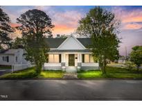 Charming white house with welcoming front porch framed by mature trees under a beautiful twilight sky at 302 N Sumner St, Selma, NC 27576