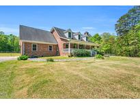 Charming two-story brick home featuring a sprawling lawn and inviting front porch with white railing at 3214 Saddle Club Rd, Mebane, NC 27302