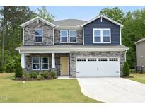 Beautiful two story home featuring a stone and blue shingle facade, a well manicured lawn and a two-car garage at 3804 Delves Ln, Raleigh, NC 27616