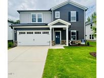 Charming two-story home with a well-manicured lawn, two-car garage, and stylish dark blue and gray siding at 3845 Rosebush Dr, Zebulon, NC 27597