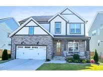 Charming two-story home with stone accents, a two-car garage, a cozy porch, and lovely curb appeal at 4816 Heathshire Dr, Raleigh, NC 27616