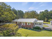 Charming brick home with a metal roof and lush green lawn and mature trees at 6418 Beaver Creek Rd, New Hill, NC 27562