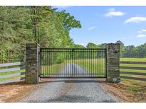 Gated entrance to a beautiful property with mature trees and a long gravel driveway leading to the home at 6600 Maynard Farm Rd, Chapel Hill, NC 27516