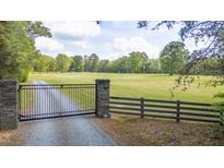 Estate home with a stone pillar gated entrance and long tree lined driveway leading to the residence at 6600(A) Maynard Farm Rd, Chapel Hill, NC 27516
