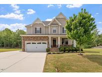 Charming two-story home with a beautifully landscaped front yard and a brick and siding facade at 7104 Rex Rd, Holly Springs, NC 27540