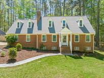 Charming brick home featuring dormer windows, a landscaped yard, and a welcoming front entrance at 10609 Lowery Dr, Raleigh, NC 27615