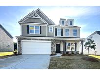 Charming two-story home with a two-car garage and stone accents, set against a clear blue sky at 1302 Cricket St, Elon, NC 27244