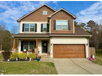 Charming two-story home with a well-manicured lawn, covered porch, and attached two-car garage at 1320 Double Oak Ln, Willow Springs, NC 27592