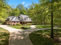 Stately brick home with a circular driveway, lush lawn and covered front porch at 1415 Meadow Wind Ln, Hillsborough, NC 27278