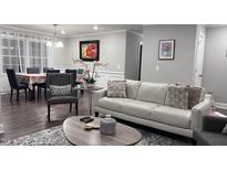 Inviting living room with a white leather sofa, chair, and wooden table, adjacent to dining area with large window at 1436 Sedwick Rd, Durham, NC 27713