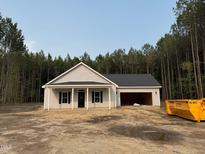 New construction home with attached garage on a spacious lot surrounded by mature trees and clear blue sky at 200 Green Pines Estates Dr, Kenly, NC 27542