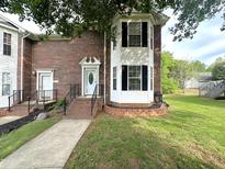 Brick townhouse with a white door, black shutters, and landscaped front yard at 208B Mallard Creek Dr, Graham, NC 27253