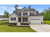 Charming two-story home with a covered front porch, beautiful landscaping, and a two-car garage at 257 Reese Dr, Willow Springs, NC 27592
