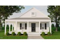 Charming home with a covered porch, black shutters and door, surrounded by lush greenery and mature trees at 329 Green Pines Estates Dr, Kenly, NC 27542