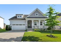 Charming home with a covered front porch, two-car garage, manicured lawn, and beautiful landscaping at 4333 Benton Mill Dr, Fuquay Varina, NC 27526