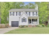 Charming two-story home with a garage, a front porch swing, and mature trees at 4711 Buttonbush Dr, Durham, NC 27712