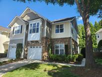 Beautiful townhouse with stone accents, attached garage, and manicured lawn against a clear blue sky at 5033 Amber Clay Ln, Raleigh, NC 27612
