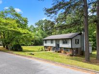 Two-story home with light siding, brick foundation, mature trees and landscaping at 820 Nuttree Pl, Raleigh, NC 27606