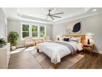 Bright bedroom featuring a ceiling fan, tray ceiling, and large windows providing lots of natural light at 8629 Dukes Lake Rd, Zebulon, NC 27597