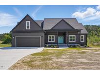 Charming exterior of home featuring a gray facade, well-manicured lawn, and a bright blue front door at 8629 Dukes Lake Rd, Zebulon, NC 27597