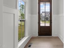 Bright entryway featuring hardwood floors, paneled walls, and a solid wood front door with neighborhood views at 9305 Field Maple Ct, Raleigh, NC 27613