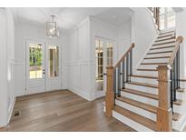 Bright foyer features hardwood floors, wainscoting, double doors and staircase with black iron spindles at 9309 Field Maple Ct, Raleigh, NC 27613