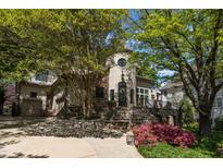 Charming home featuring a stone and stucco exterior, mature trees, and landscaped front yard at 2117 Buckingham Rd, Raleigh, NC 27607