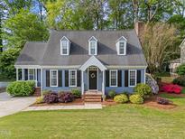 Charming blue two-story home with well-manicured lawn, lush landscaping, and black shutters at 2908 Bolo Trl, Raleigh, NC 27615