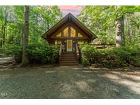Charming cabin with gable windows, wood siding, surrounded by lush greenery, and a gravel driveway at 300 Rabbit Run, Pittsboro, NC 27312