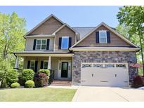 Charming two-story home featuring stone accents, a covered porch, and an attached two-car garage at 335 Gwendolyn Way, Fuquay Varina, NC 27526
