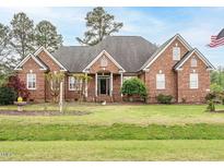 Charming brick home with a well-maintained lawn and mature landscaping under a partly cloudy sky at 4501 Forest Dr, Holly Springs, NC 27540