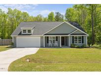 Charming single-story home with a well-manicured lawn and inviting front porch with rocking chairs at 479 Kotata Ave, Bunnlevel, NC 28323