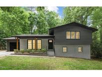 Charming home featuring an attached garage, gray brick, black trim, and lush green lawn at 6421 Arrington Rd, Raleigh, NC 27607