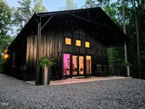 Stunning exterior of a modern black home featuring a gravel driveway and inviting porch with rocking chairs at 665 Lonach Ln, Roxboro, NC 27574