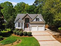 Charming two-story home featuring a stone facade, two-car garage, manicured lawn, and mature trees at 6819 Rainwater Rd, Raleigh, NC 27615