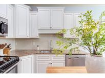 Bright kitchen features white cabinets, granite countertops, stainless steel appliances, and tile backsplash at 715 Barlang Cir, Fuquay Varina, NC 27526