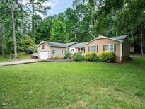 Ranch-style home featuring a well-manicured lawn, mature trees, and a two-car garage at 725 Van Thomas Dr, Raleigh, NC 27615