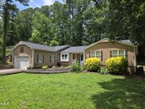 Charming home with landscaped yard, mature trees, and two car garage at 725 Van Thomas Dr, Raleigh, NC 27615