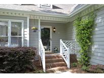 Charming home featuring a brick staircase leading to the front door, complemented by lush landscaping and a hanging flower basket at 104 Silver Fox Ct, Cary, NC 27511