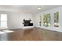 Bright living room features hardwood floors, fireplace, and large windows with natural light at 104 Silver Fox Ct, Cary, NC 27511