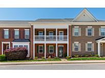 Charming two-story brick townhome featuring double balconies and a well-manicured lawn and flowering bushes at 1322 Regulator St, Raleigh, NC 27603