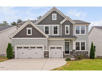 Stunning two-story home featuring a three-car garage, stone accents, and manicured landscaping at 1711 Sandoval Dr, Durham, NC 27703