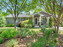 Charming home featuring lush landscaping and inviting front porch, with mature trees providing shade at 2128 Watkins St, Raleigh, NC 27604