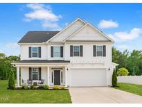 Charming two-story home features white siding, black shutters, covered porch, and attached two car garage at 214 Thumper Way, Clayton, NC 27520