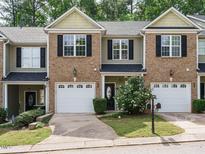 Charming townhouse with brick facade, black shutters, and single-car garage, surrounded by lush landscaping at 23 Great View Ct, Clayton, NC 27527