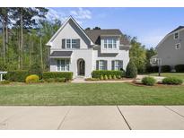 Charming white brick two-story home featuring a landscaped front yard with mature trees and dark shutters at 3138 Curling Creek Dr, Apex, NC 27502