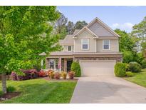 Charming two-story home with a well-manicured lawn, flowering shrubs, and an attached two-car garage at 504 Applecross Dr, Mebane, NC 27302
